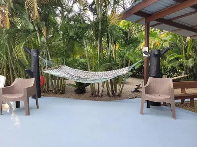 a hammock in a resort with chairs and trees at Arenal Family Home - Families & Friends Gateway in Fortuna