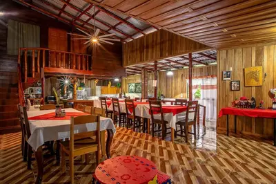 a dining room with wooden floors and tables and chairs at Arenal Family Home - Families & Friends Gateway in Fortuna