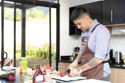 a man in a kitchen preparing food on a cutting board at Villa Arthur La Fortuna in Fortuna