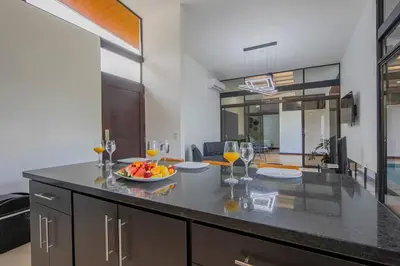 a kitchen with a table with a bowl of fruit and wine glasses at Villa Arthur La Fortuna in Fortuna