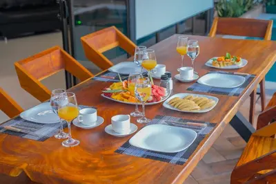 a wooden table with plates of food and glasses of orange juice at Villa Arthur La Fortuna in Fortuna