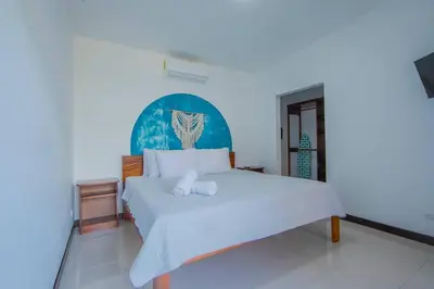 a bedroom with a white bed with a blue headboard at Villa Arthur La Fortuna in Fortuna