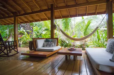 a porch with a hammock and a couch and a table at Villas Santa Teresa in Santa Teresa Beach