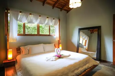 a bedroom with a large white bed with a mirror at Villas Santa Teresa in Santa Teresa Beach