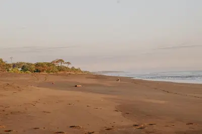 a beach with people laying on the sand at In the HEART of Jaco at Villas Paraiso in Jacó
