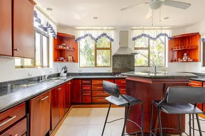 a kitchen with wooden cabinets and a counter with chairs at Private Beach Mansion Ocean View at Tambor Hills in Tambor