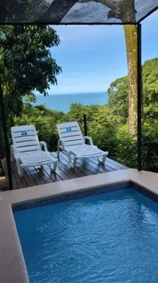 two chairs and a swimming pool with a view of the ocean at Villa Jalapa 