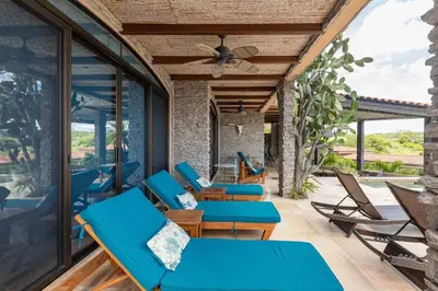 an outdoor patio with blue chairs and tables at Casa De Los Sueos in Playa Hermosa