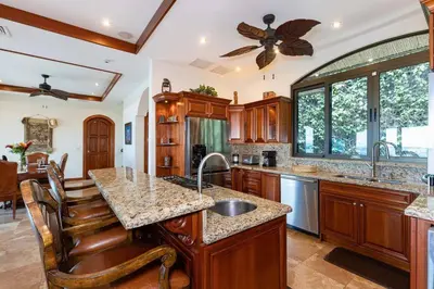 a kitchen with wooden cabinets and a ceiling fan at Casa De Los Sueos in Playa Hermosa