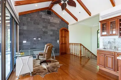 a living room with a desk and a stone wall at Casa De Los Sueos in Playa Hermosa