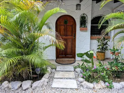 a house with a wooden door and some plants at Tico Tiki Vacation Villa, 5 Bedroom in Sámara