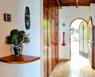 a hallway with a vase on a wooden shelf next to a door at Tico Tiki Vacation Villa, 5 Bedroom in Sámara