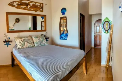 a bedroom with a bed in a room with a mirror at Tico Tiki Vacation Villa, 3 Bedroom in Sámara