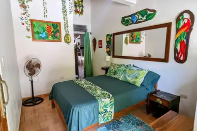 a bedroom with a bed and a mirror and a fan at Tico Tiki Vacation Villa, 3 Bedroom in Sámara