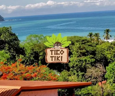 a sign for a tikiiki restaurant with the ocean in the background at Tico Tiki Vacation Villa, 3 Bedroom in Sámara