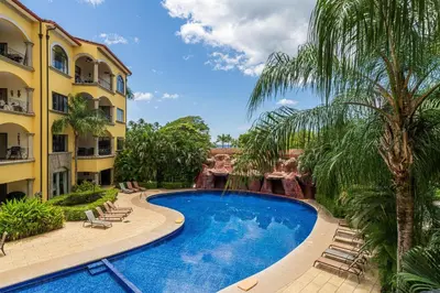 a swimming pool in a resort with chairs and palm trees at Sunrise 42 - 2 Bedroom Ocean View Condo in Tamarindo