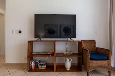 a living room with a tv and a table and chairs at Sunrise 42 - 2 Bedroom Ocean View Condo in Tamarindo