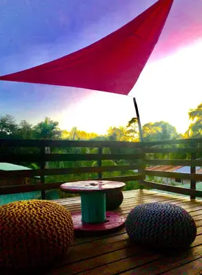 a table and chairs on a deck with an umbrella at El Reinas by Sugar's Monkey in Playa Grande