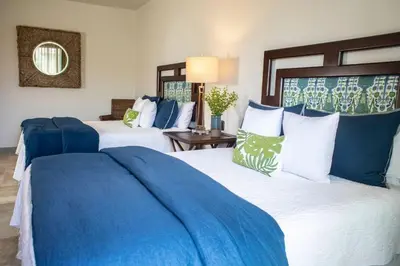 two beds in a hotel room with blue and white pillows at Las Ventanas del Mar-Ridge Condo #13 in Santo Domingo
