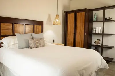 a bedroom with a white bed with a wooden headboard at Las Ventanas del Mar-Ridge Condo #13 in Santo Domingo