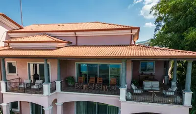 a house with a balcony with chairs and tables at Las Ventanas del Mar-Ridge Condo #13 in Santo Domingo