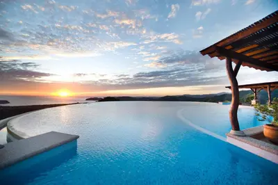 a swimming pool with a sunset in the background at Las Ventanas del Mar-Ridge Condo #13 in Santo Domingo