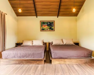 two beds sitting next to each other in a room at Cabaña Rincón Verde - La Fortuna in Fortuna