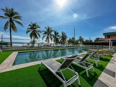 a swimming pool with lounge chairs and palm trees at Ocean Front, Luxurious Condo in Downtown Jaco! in Jacó