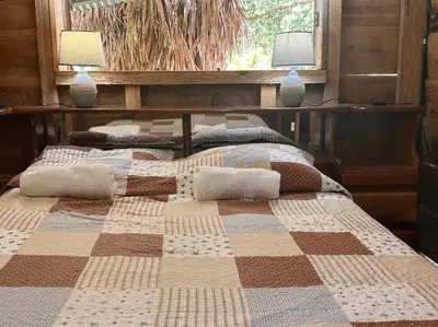 two beds in a bedroom with a checkered blanket at Motel Rio Celeste in Bijagua
