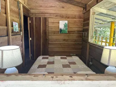 a room with a bed and two lamps and a window at Motel Rio Celeste in Bijagua