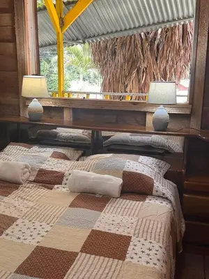 two beds in a room with two lamps and a window at Motel Rio Celeste in Bijagua