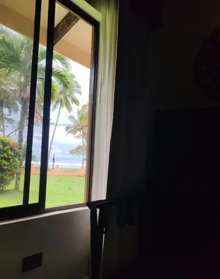 a window with a view of the ocean and palm trees at Marenaz Oceanfront Resort in Esterillos Este