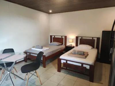 a room with two beds and a desk and a chair at Pura Vida Rentals in Cabuya
