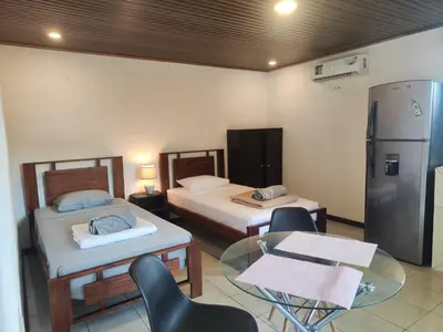 a room with two beds and a glass table and a refrigerator at Pura Vida Rentals in Cabuya