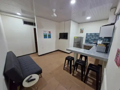 a living room with a couch and a table and stools at Manuel Antonio Tropical Twins in Quepos