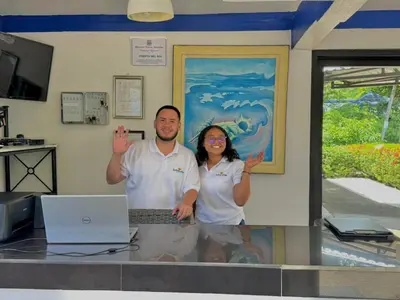 a man and woman standing next to a counter with a laptop at La Puerta del Sol in Coco