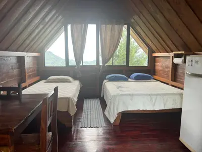 two beds in a room with two windows at Vista Hermosa Lodge in Aserrí