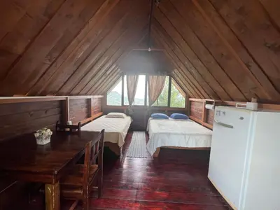 a room with two beds and a table and a refrigerator at Vista Hermosa Lodge in Aserrí