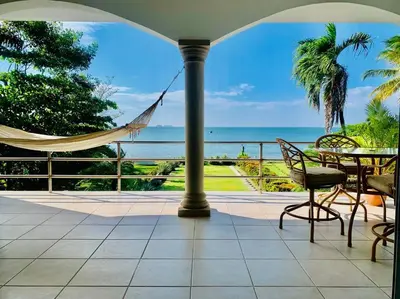 a patio with a hammock and a view of the ocean at Gorgeous Beachfront Home in Playa Potrero in Playa Flamingo
