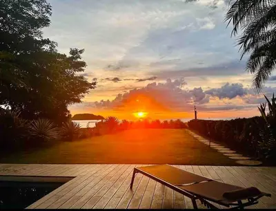 a bench on a deck with the sunset in the background at Gorgeous Beachfront Home in Playa Potrero in Playa Flamingo