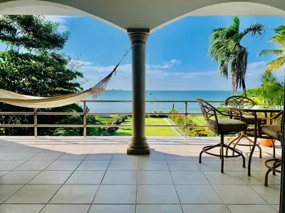 a patio with a hammock and a view of the ocean at Gorgeous Beachfront Home in Playa Potrero in Playa Flamingo