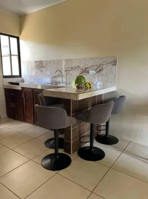 a kitchen with a counter and two bar stools at Apartamentos del Sol #2 in Tilarán