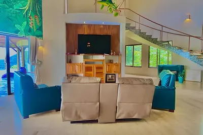 a living room with two blue chairs and a television at MonkeyRanch LuxLodge in Dominicalito