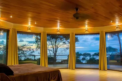 a bedroom with yellow curtains and large windows at MonkeyRanch LuxLodge in Dominicalito