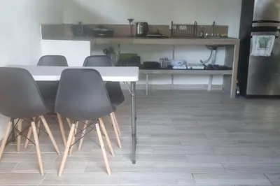 a table and chairs in a room with a kitchen at Cabinas Guacamaya in Cabuya
