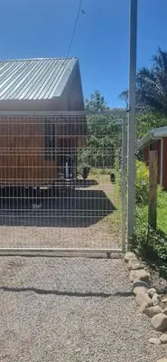 a fence in front of a building with animals in it at Cabinas Guacamaya in Cabuya