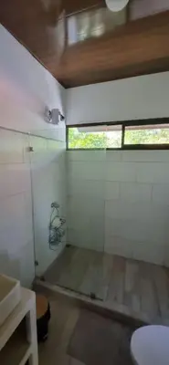 a bathroom with a toilet and a window in it at Cabinas Guacamaya in Cabuya