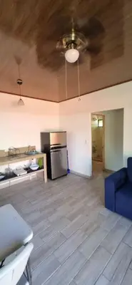 a living room with a blue couch and a kitchen at Cabinas Guacamaya in Cabuya