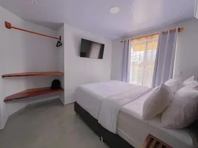 a white bedroom with a bed and a window at Monstera Apartments Monteverde in Monteverde Costa Rica