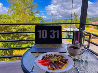 a plate of food on a glass table with a laptop at Monstera Apartments Monteverde in Monteverde Costa Rica